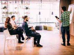 Young casual businessman pitching concept to room of team members